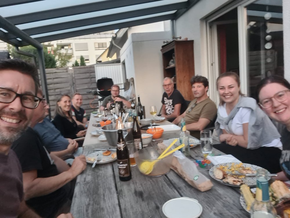 10 Personen sitzen um einen Eßtsich
