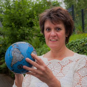 Portraitaufnahme von Iris Laier in einem Garten mit einer kleinen Weltkugel in den Händen