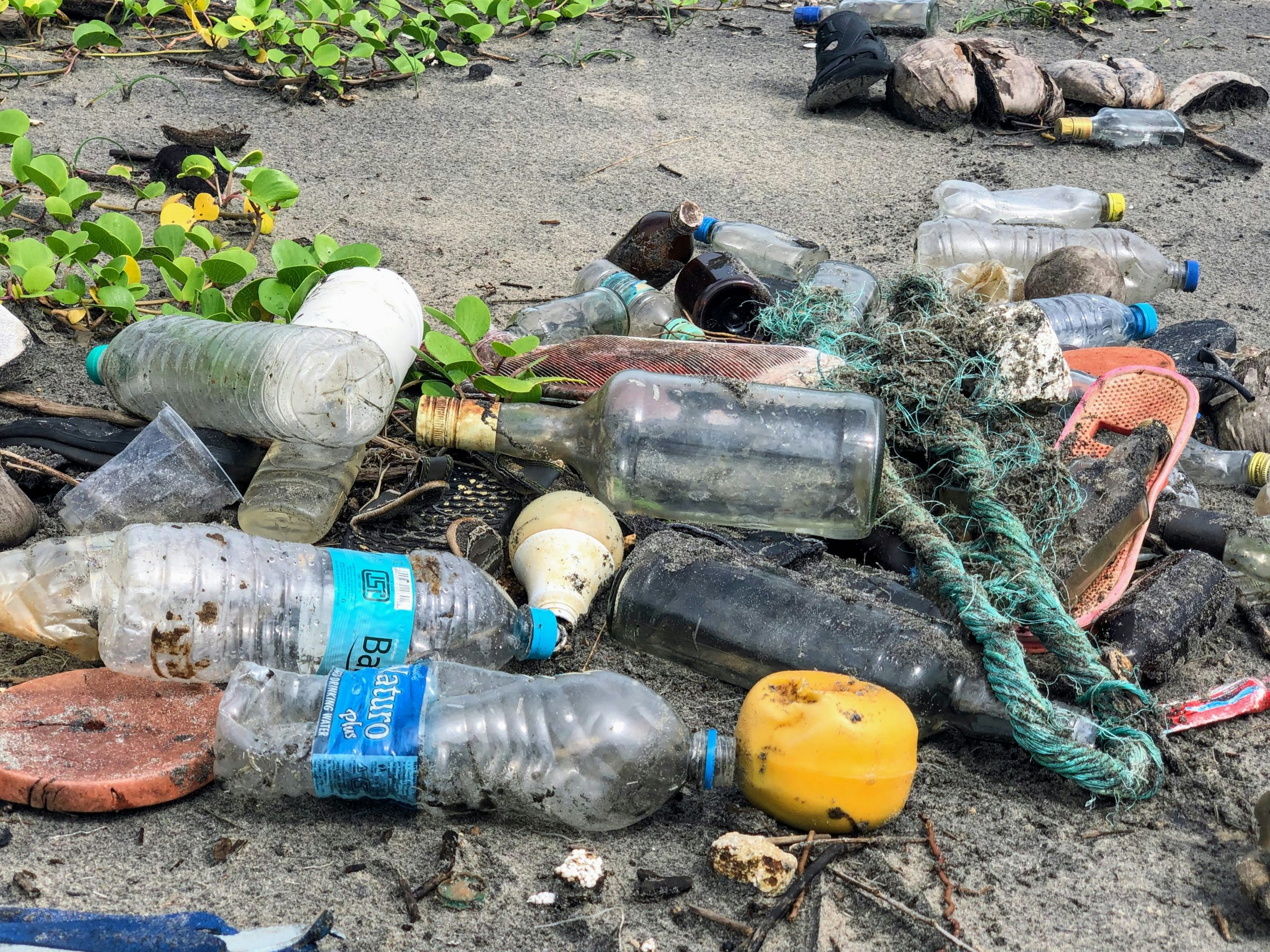 Müllberg aus Plastikflaschen, Glasflaschen und ähnlichem an einem Gewässer