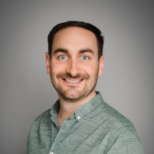 Portraitaufnahme Simon Rosen vor grauem Hintergrund